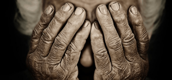 Distressed elderly person covering his face
