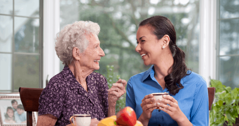 An elderly chatting happily with a caregiver