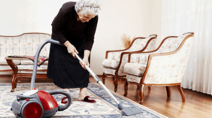 Elderly woman vacuuming
