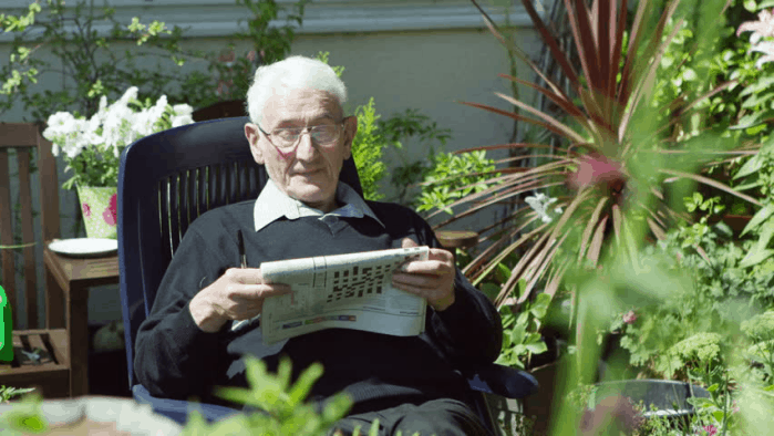 An elderly solving a crosswords puzzle in his armchair