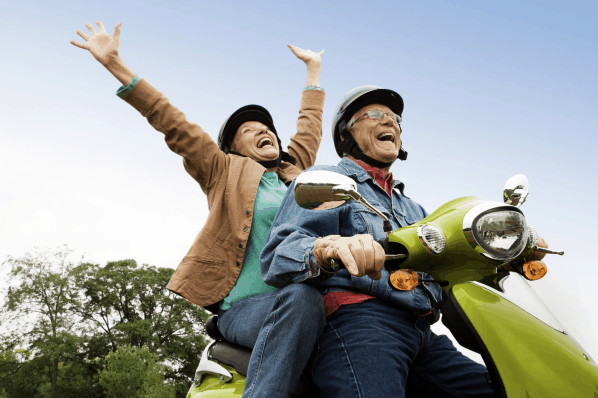 An elderly couple enjoying the travel on a moped