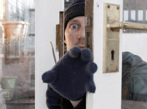 A burglar grabbing for valuables from a half-opened door