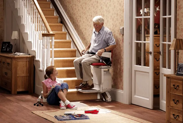 An elderly using a stairlift with his granddaughter