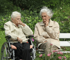 Two elderly women sitting on a bench while talking
